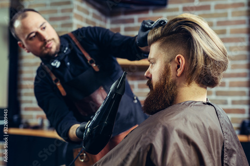 Barber drying male hair in hairdressing salon