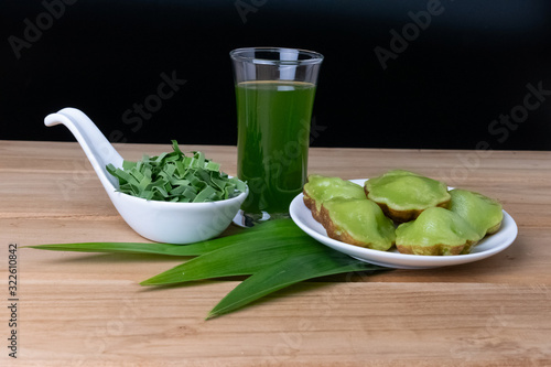 Photography Siam Pandan Thai dessert with plate, water and pandan leaves on a dark wooden floor