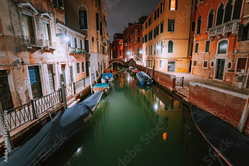 Venezia Italy. Narrow channel and gondola boats in lagoon city venice at night. Vivid colored old brick buildings around © Igor Tichonow