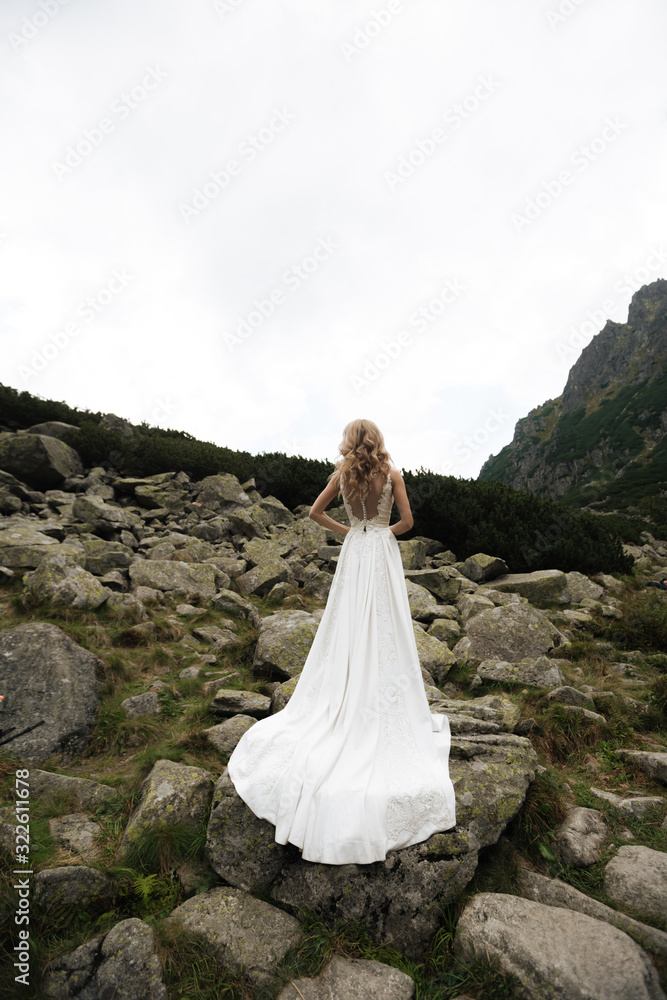 bride in white wedding dress closed her eyes on the background of rocks and sea.