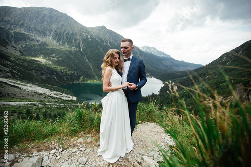 The bride and groom near the lake in the mountains. A couple together against the backdrop of a mountain landscape. Morskie Oko Lake. Tatra mountains in Poland.