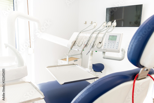 blue dentist armchair with instruments in white cabinet