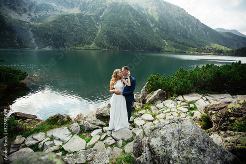 The bride and groom near the lake in the mountains. A couple together against the backdrop of a mountain landscape. Morskie Oko Lake. Tatra mountains in Poland.