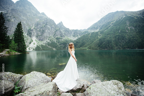 Portrait of a beautiful bride with a wedding bouquet. Blonde girl with curly hair and fashion makeup.