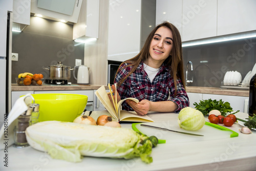 Young woman cooking  food using a notepad as help in her kitchen