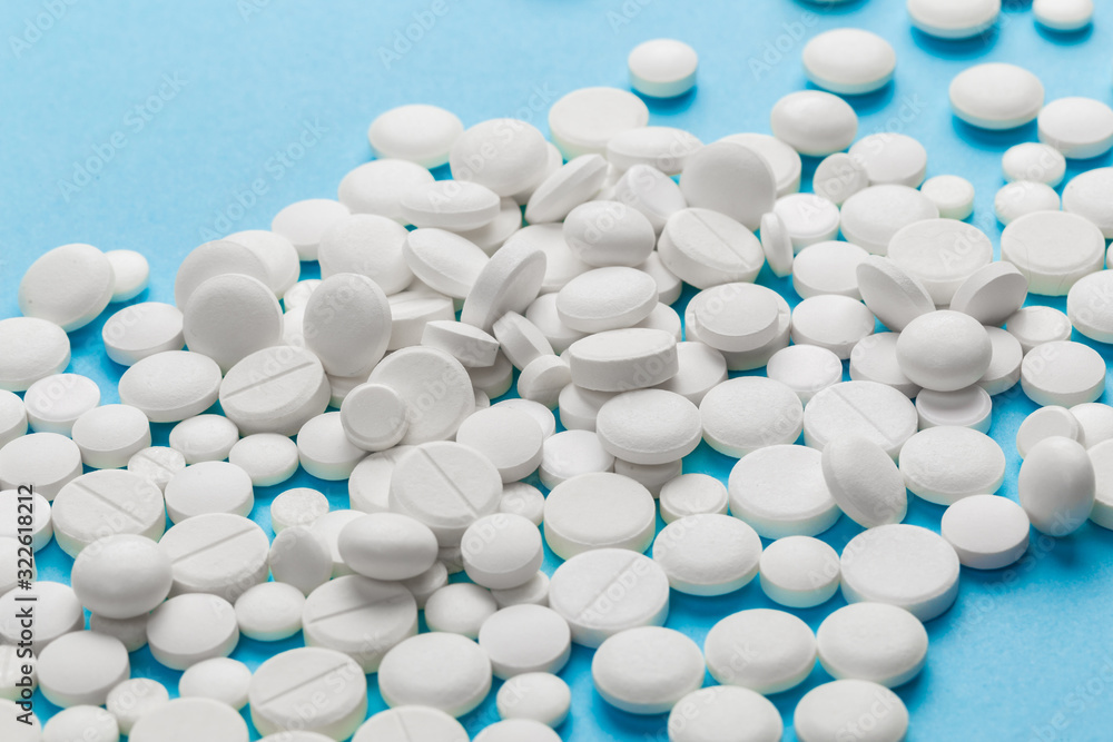 scattered white pills on a blue table. Layout for special offers such as advertising or other ideas. The concept of medicine, pharmacy and healthcare. Space for copy. flat lay for text or logo. scattered white pills on a blue table. Layout for special offers such as advertising or other ideas. The concept of medicine, pharmacy and healthcare. Space for copy. flat lay for text or logo.
