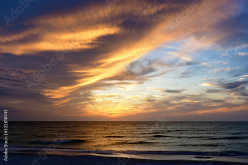 Fototapeta Naklejka Na Ścianę i Meble -  Orange sunset illuminating  storm clouds over the Gulf of Mexico at St. Pete Beach, Florida.