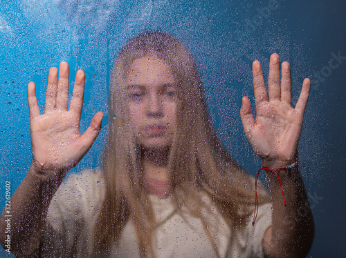 Portrait of a girl through a transparent surface covered with frost