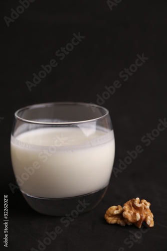 glass of walnut milk in color background
