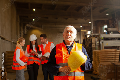 Portrait of factory worker with hard hat in his hands