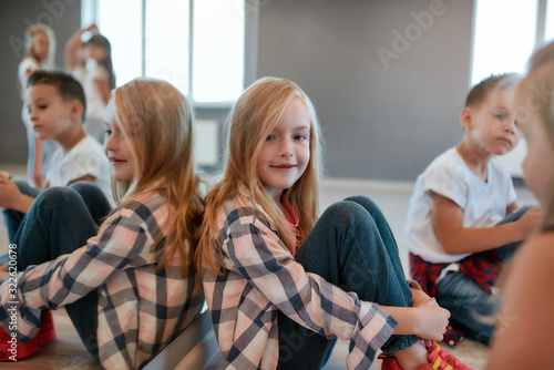 Taking a break. Portrait of happy cute little girl in checkered shirt looking at camera and smiling while having a choreography class in the dance studio