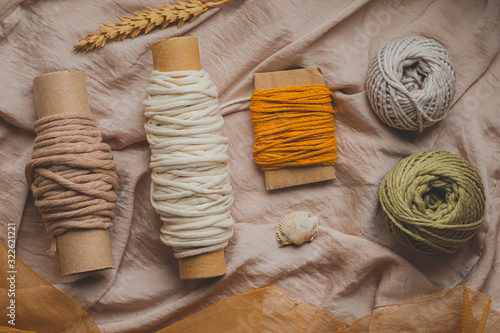  Macrame ropes in various colors, top view. Mustard, olive and white crochet threads in beautiful pastel backdrop, flat lay image