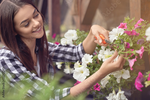 Woman pruning plants in flowerpots outdoors.