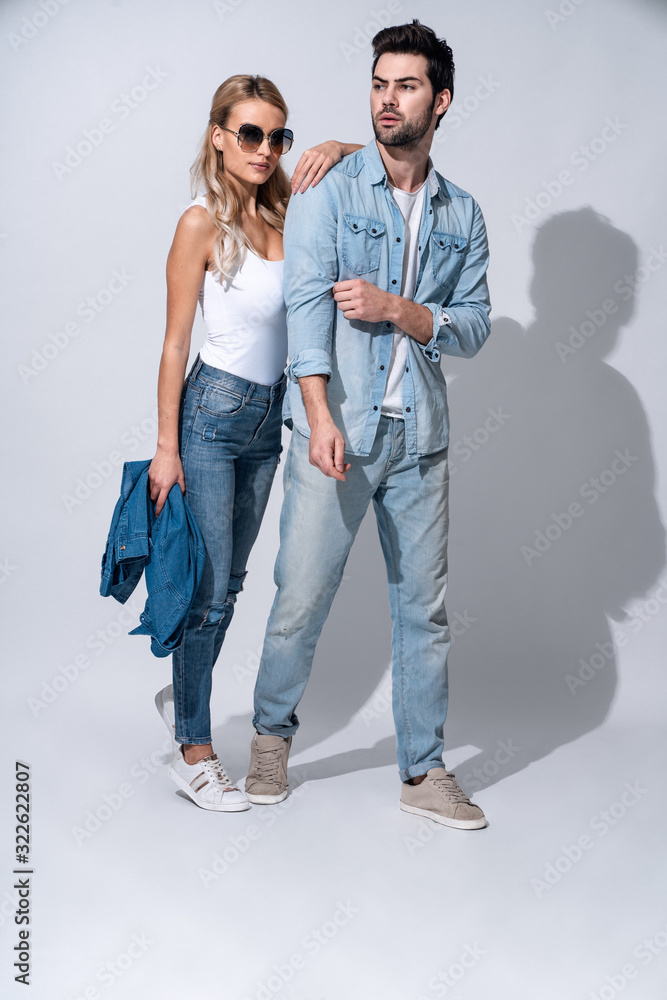 Fototapeta premium Looking amazing. Full length of beautiful young couple bonding while standing against grey background