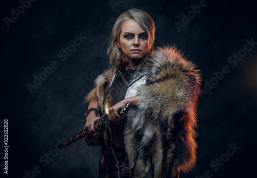 Fantasy woman knight wearing cuirass and fur, holding a sword scabbard ready for a battle. Fantasy fashion. Cosplayer as Ciri from The Witcher.