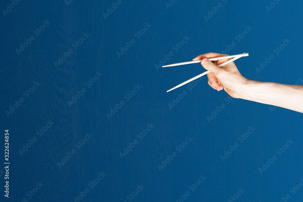abstract hand holding the empty pair of wooden chopsticks isolated on color background, abstract hand holding the empty pair of wooden chopsticks isolated on color background,