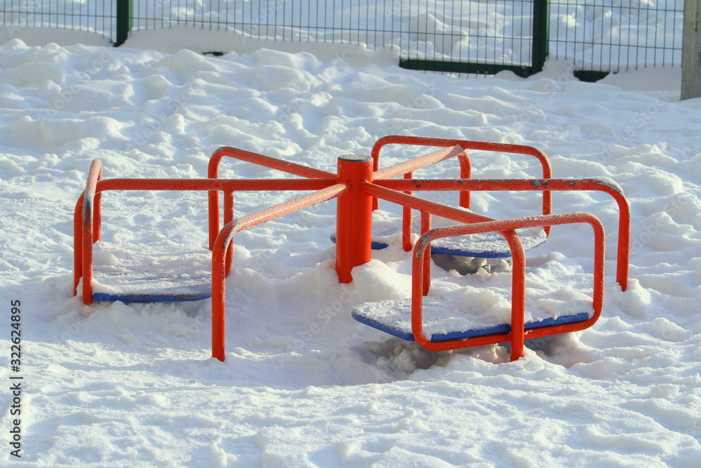 Children's red metal carousel covered with snow. Children's red metal carousel covered with snow.