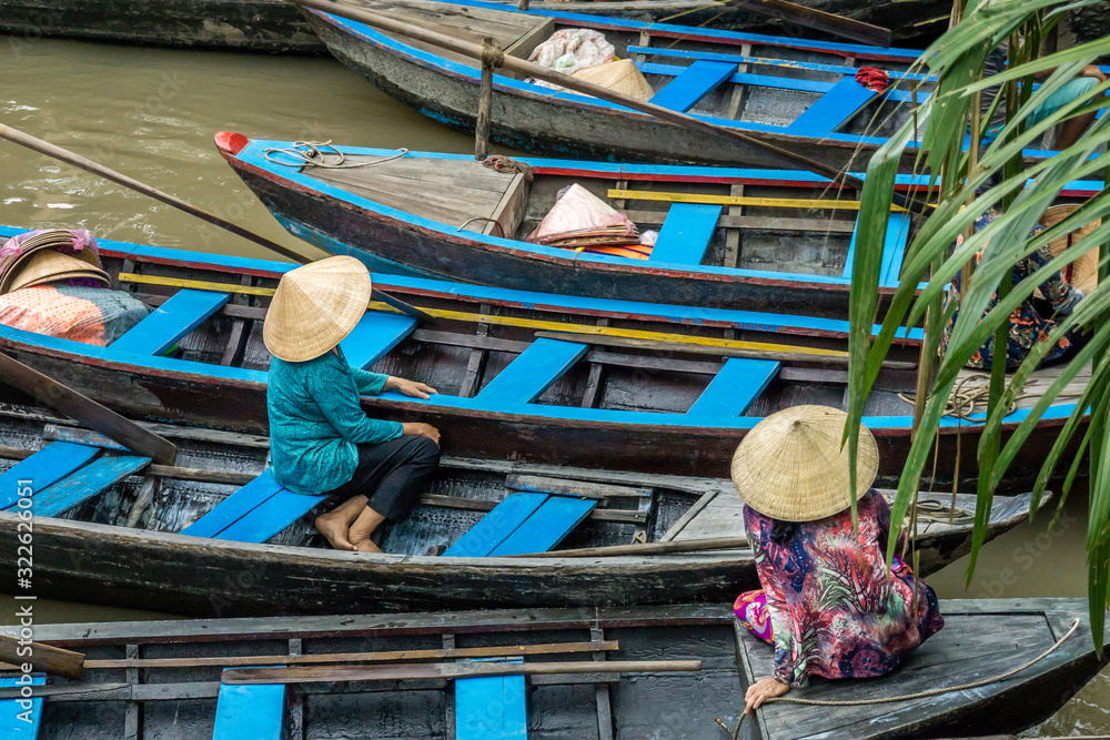 Two women resting on their wooden boats in the Mekong Delta