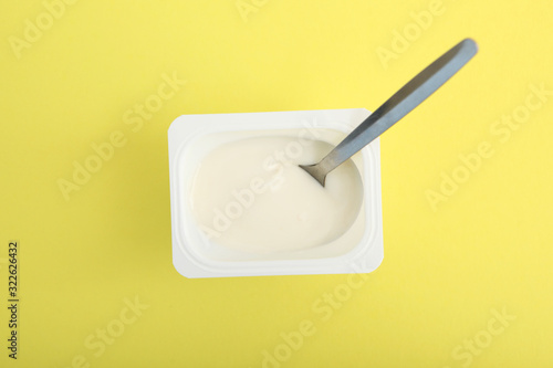 Tasty yogurt in a plastic glass on a colored table top view. Place to insert text. Useful snack.