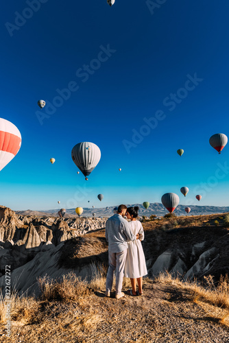 Couple in love among balloons. Loving couple rear view. Couple in love in Cappadocia. Couple in Turkey. Honeymoon in the mountains. Man and woman traveling. Flying on balloons. Traveling the world