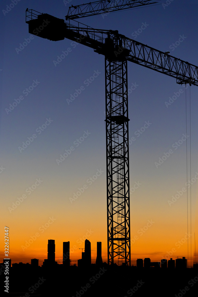 Vertical image of the sunset in the Valdebebas neighborhood in Madrid. Area under construction with mounted cranes