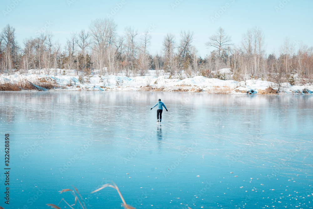 A young man skates on a frozen lake.