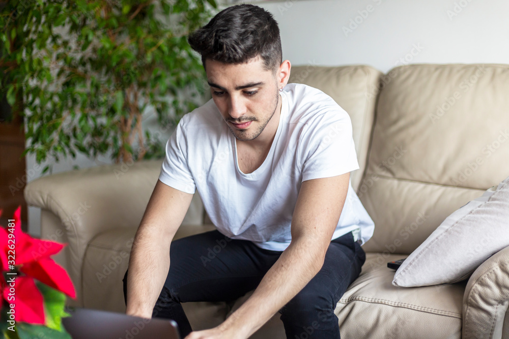 Handsome young man using computer while sitting on the sofa Handsome young man using computer while sitting on the sofa