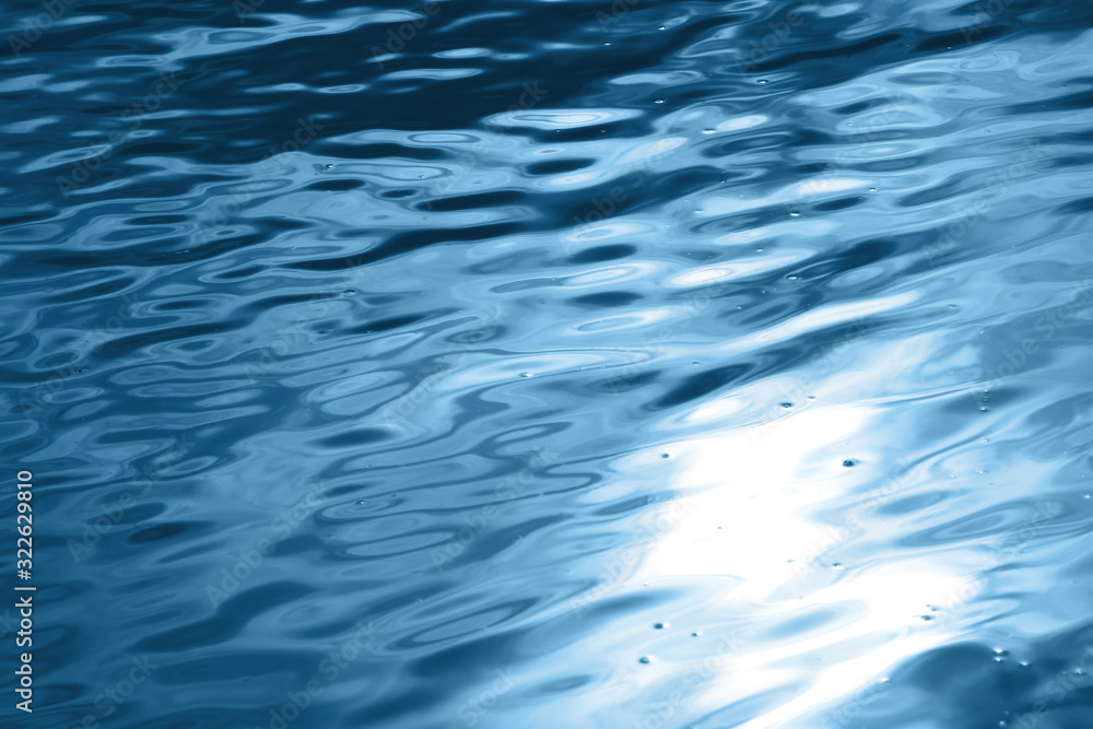 Blue wavy water surface with sun glare