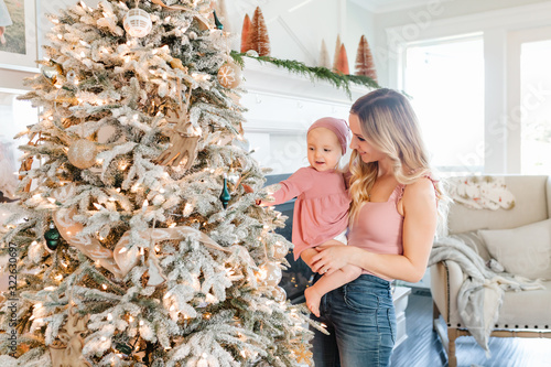 Mother Holding baby daughter by christmas tree