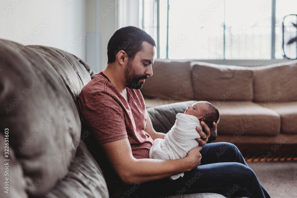 Mid-30?s dad with beard holding swaddled infant Mid-30?s dad with beard holding swaddled infant