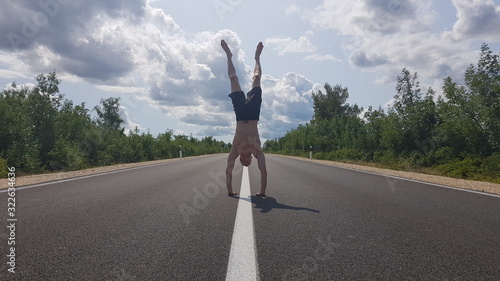 Young man performing an handstand on the middle of the road in Croatia.