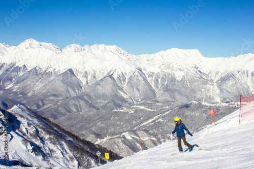 Beautiful view of the snowy mountain peak in the Alps with a snowboarder. Wonderful sunny weather. Sochi