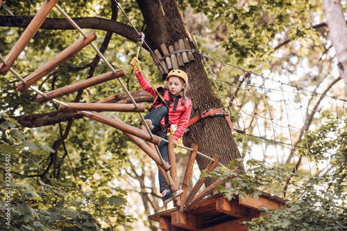 Every childhood matters. Happy child in summer. Small boy enjoy childhood years. Child climbing on high rope park. Hiking in the rope park girl in safety equipment.