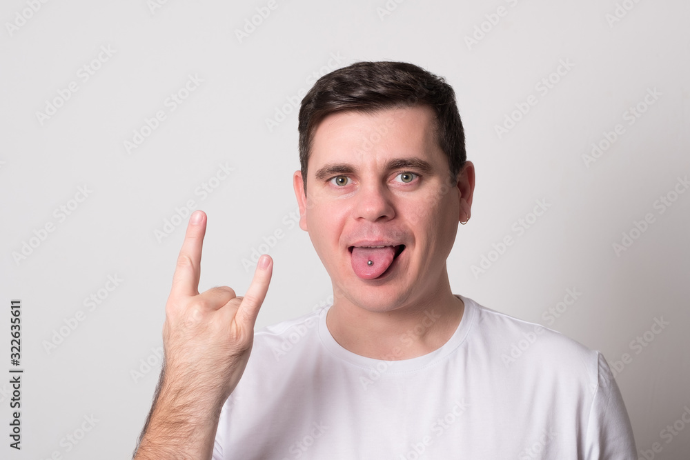 Emotional young man. Charming man shows tongue with a piercing. Emotional young man. Charming man shows tongue with a piercing.