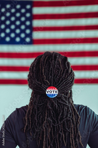 Black citizen looking at American Flag with Vote button photo