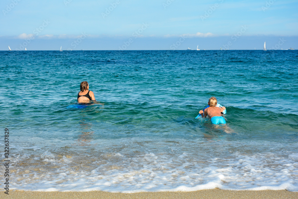 Two children play with a swimming board in the sea Two children play with a swimming board in the sea