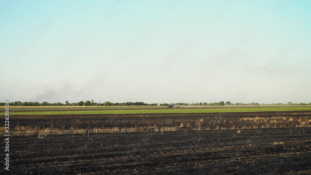 Old tractor is plowing field. The machine preparing land for sowing. Farmland industry, seasonal yield, working technique. Wide shot of huge field on farm. Tractor plough a field in early spring. Old tractor is plowing field. The machine preparing land for sowing. Farmland industry, seasonal yield, working technique. Wide shot of huge field on farm. Tractor plough a field in early spring.