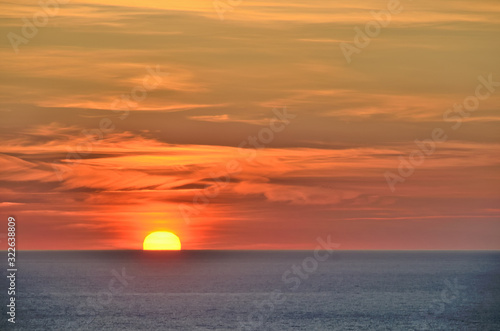Fototapeta Naklejka Na Ścianę i Meble -  Rising sun over the sea. Beautiful  clouds. The morning sun illuminates the clouds with light