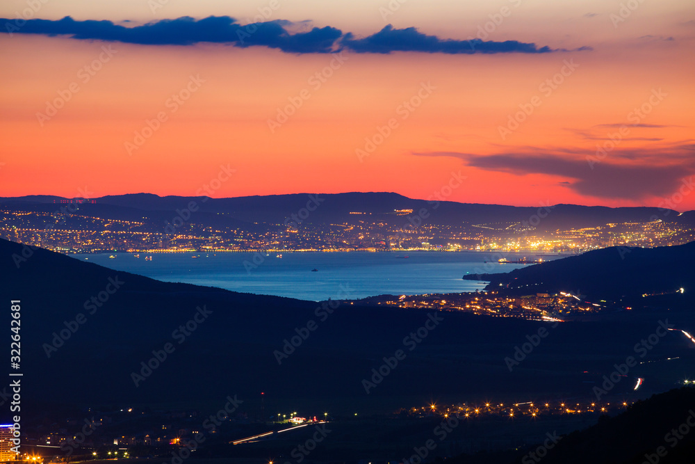 panorama of Novorossiysk Bay at night from the Caucasus mountains. bright lights, reflection in the water. car lights, mountains. roads. 