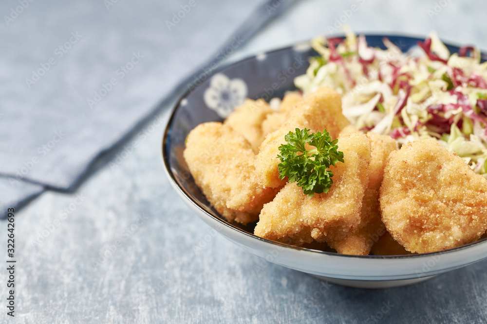 Chicken nuggets with raw salad and french fries on bright wooden background. Copy space. Chicken nuggets with raw salad and french fries on bright wooden background. Copy space.