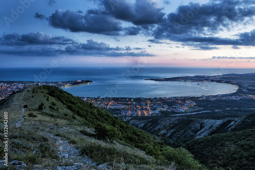 Gelendzhik Bay from a bird's eye view.  photo at sunset. Caucasus mountains in the foreground. illuminated streets of the city. dark blue sky, beautiful dark clouds © Александр Трихонюк