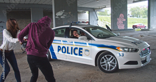 Wallpaper Mural Close-up african man thief trying to rip out the bag from a screaming scared girl in front of the police. Cheerful policemen eating donuts laughing and sitting in patrol car. Torontodigital.ca