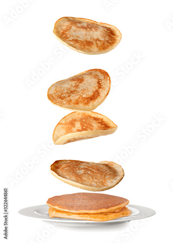 Plate with falling pancakes on white background photo