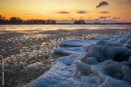 Sunrise and frozen river. Beautiful winter landscape with lake in morning time. Daybreak