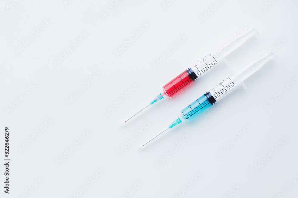 Two syringes filled with blue and red liquids on white background Two syringes filled with blue and red liquids on white background