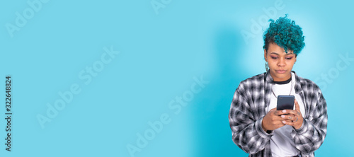 Fotografie african american girl or woman with mobile phone or smartphone isolated on blue