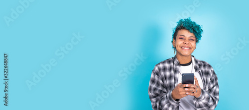 Fotografie african american girl or woman with mobile phone or smartphone isolated on blue