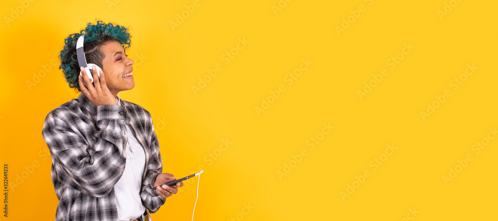 young brunette girl with mobile phone and headphones isolated on background young brunette girl with mobile phone and headphones isolated on background