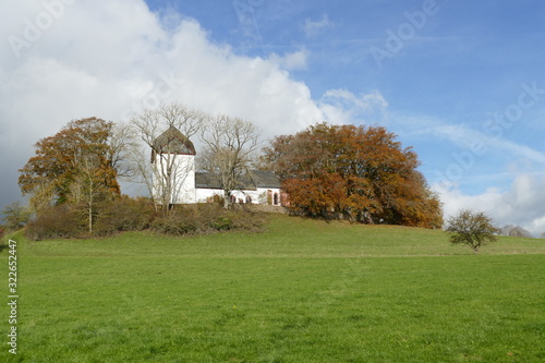 Alte Kirche mit Bäumen in Alendorf / Eifel photo