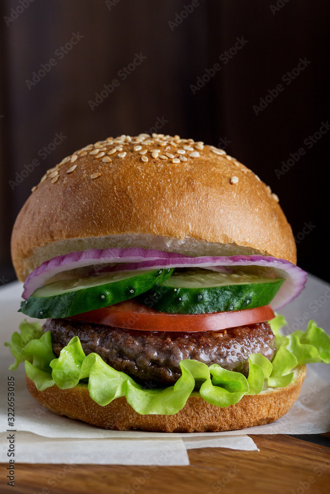Close up burger with beef, green salad, cucumber, tomato and red onion Close up burger with beef, green salad, cucumber, tomato and red onion